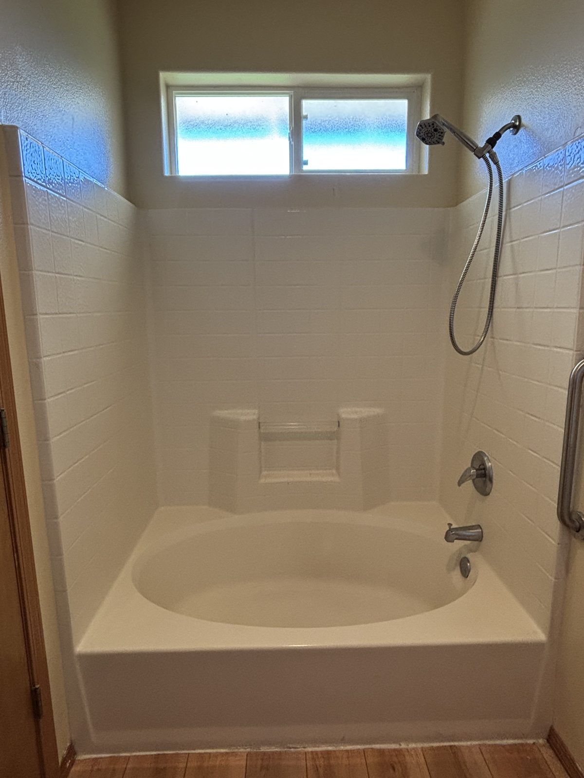 Before: old fiberglass tub and shower combo with a molded seat and handheld shower