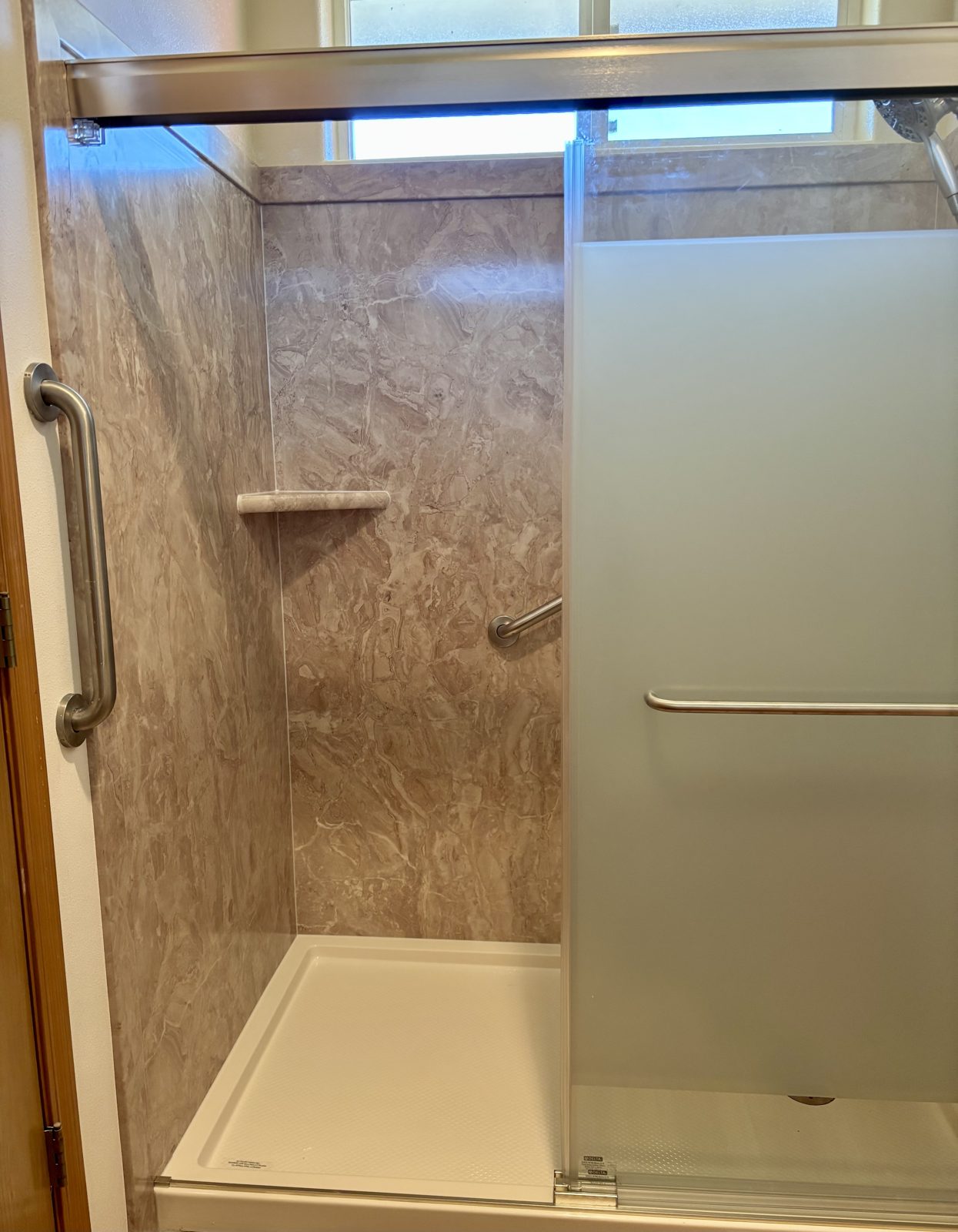 Walk-in shower with grab bar, corner shelf, and handheld shower head